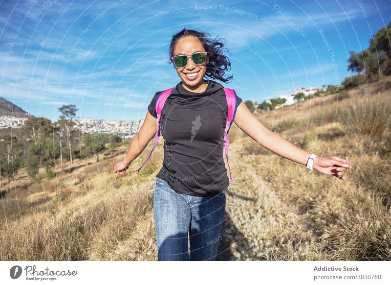 Smiling ethnic woman enjoying nature in countryside backpacker footpath carefree sunny smile cheerful female trip stand explore happy dry fun lady asian