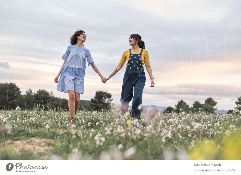 Positive women running through meadow happy excited carefree having fun summertime slender nature cheerful toothy smile harmony field friendship free time