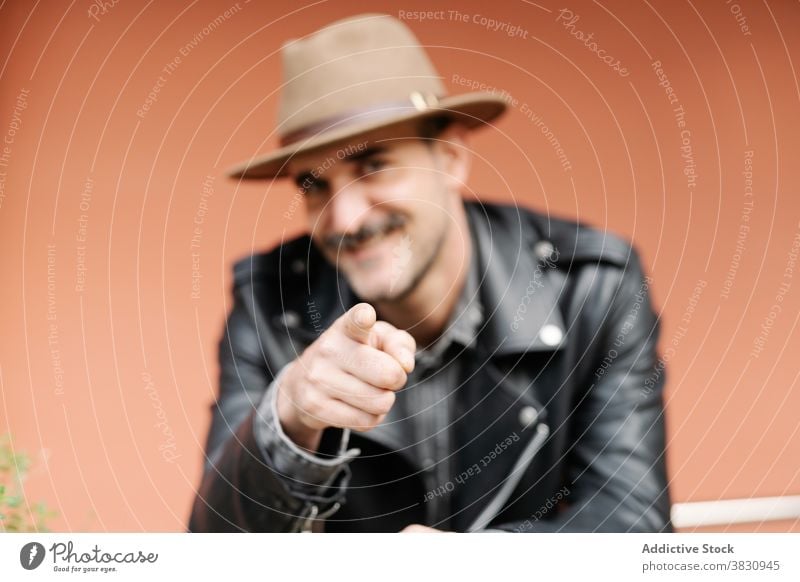 Cheerful man with mustache pointing at camera cheerful point at camera happy charismatic metrosexual beard hat you pick choose trendy modern confident content