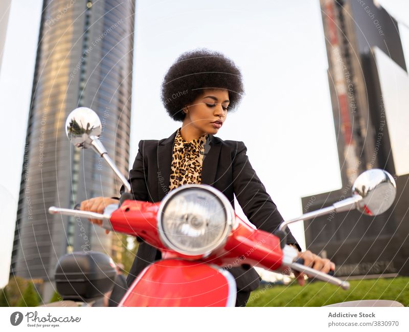 Serious black woman on red scooter motorbike vintage confident serious concentrate classic style elegant thoughtful female appearance individuality vehicle