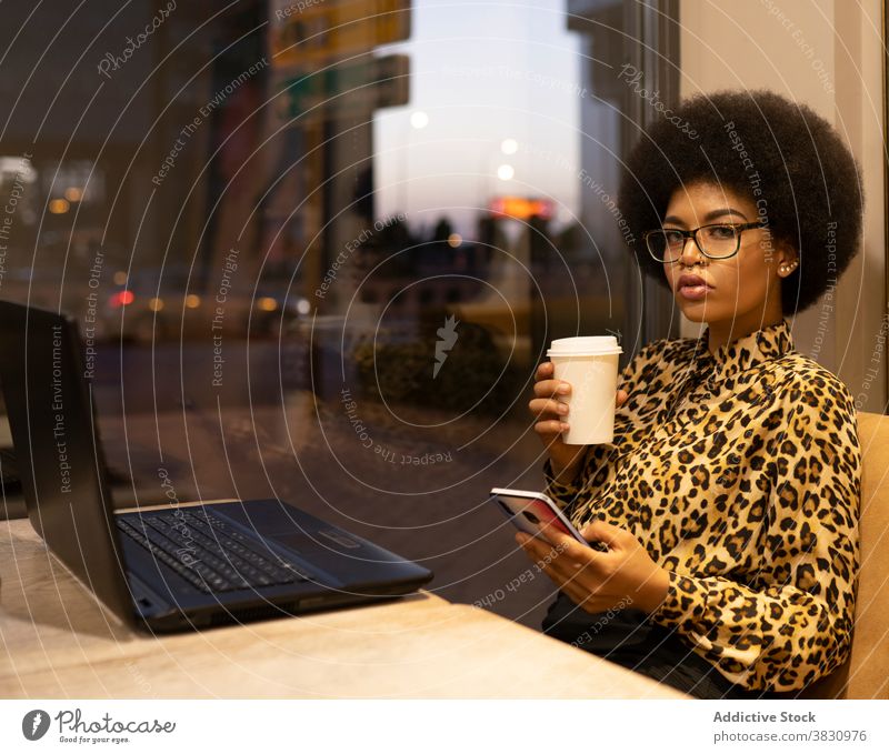 Pensive black woman using smartphone in cafe serious freelance remote confident internet texting coffee entrepreneur female surfing browsing cup afro hair