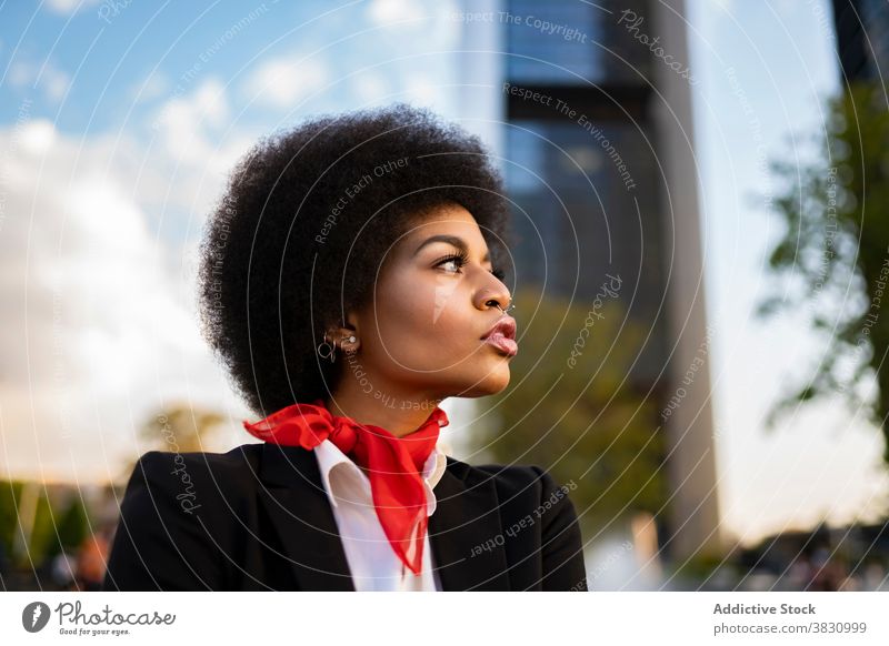 Stylish black woman standing near in city serious formal confident style cool elegant calm thoughtful appearance female afro piercing individuality brunette