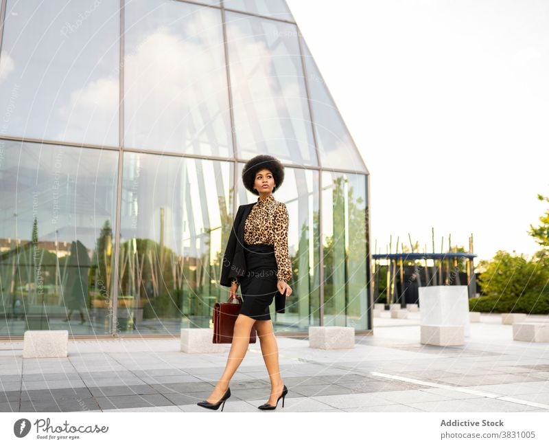 Pensive black businesswoman in formal outfit near modern tower entrepreneur executive optimist style confident respectable thoughtful female suit work walk