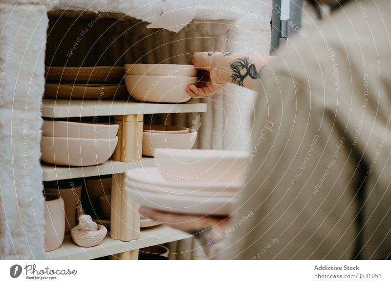 Crop ceramist with bowl in workshop pottery ceramic clay artisan craftsmanship shelf creative studio professional skill design occupation handmade job hobby