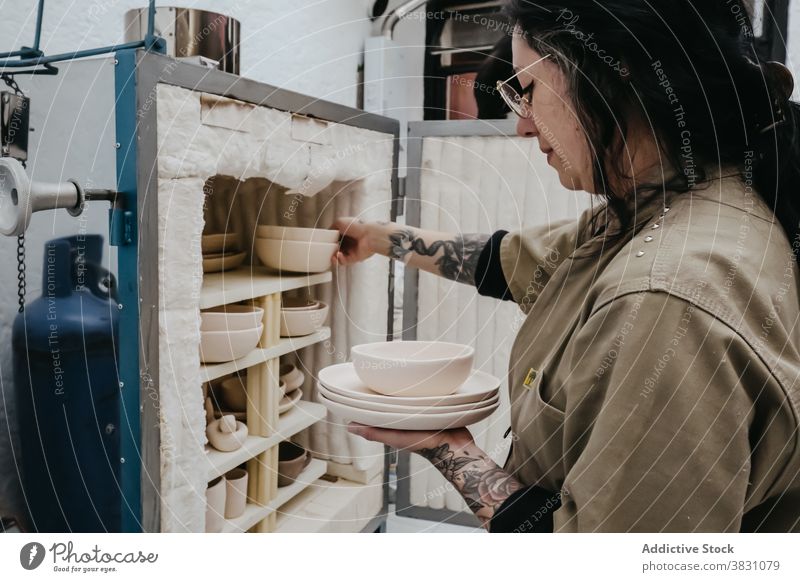 Crop ceramist with bowl in workshop pottery ceramic clay artisan craftsmanship shelf creative studio professional skill design occupation handmade job hobby