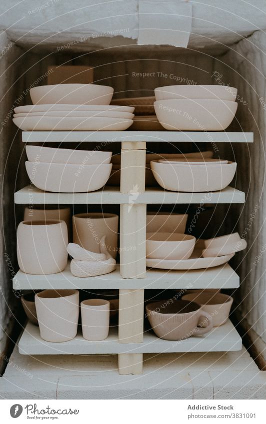 Handmade pottery on shelf in workshop earthenware ceramic clay tableware kitchenware studio creative composition set hobby assorted craft arrangement collection