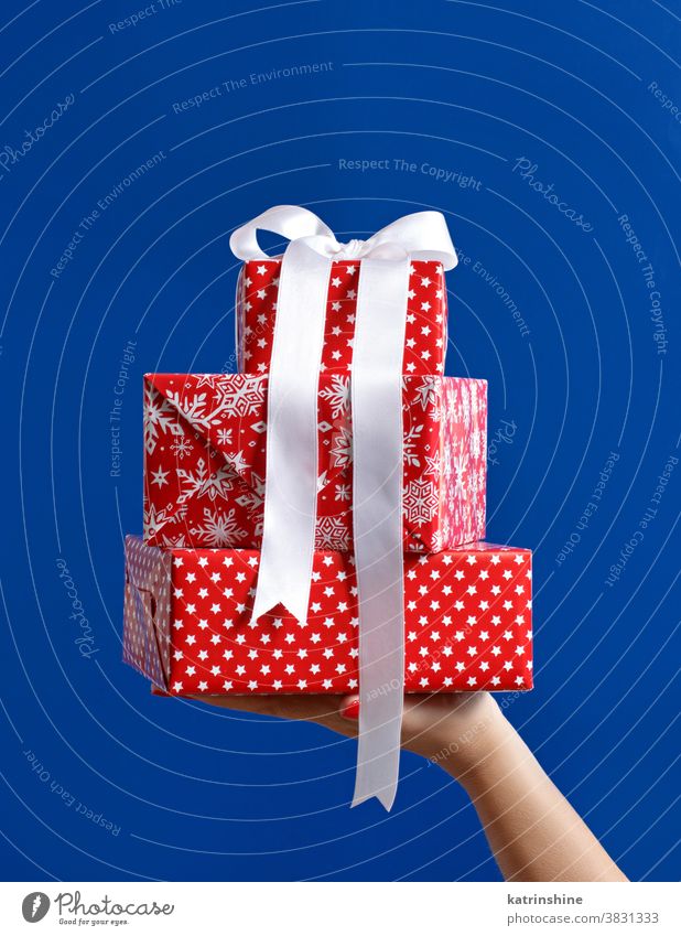 Hand holding red gift boxes on blue background Gift box christmas hand faceless bow ribbon isolated close up stars table Wrapped Present Holiday Package Nobody