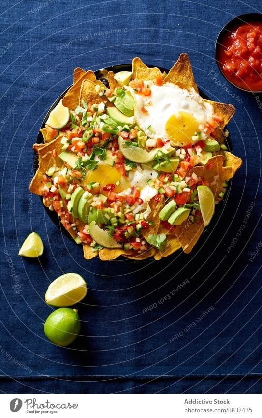 Chilaquiles dish with avocado food chilaquiles mexican tortilla top view breakfast overhead black beans nachos cilantro sauce fried meal chips fresh salsa