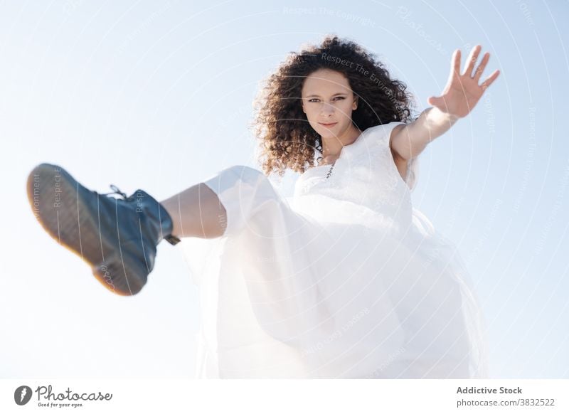 Joyful happy woman jumping looking at camera rebel freedom cool ethnic stretch white dress summer positive young cheerful fun modern healthy mixed race