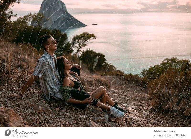 Carefree couple resting on hill near sea style sunset relax enjoy carefree love cuddle shore relationship tranquil stone rough summer romantic coast nature