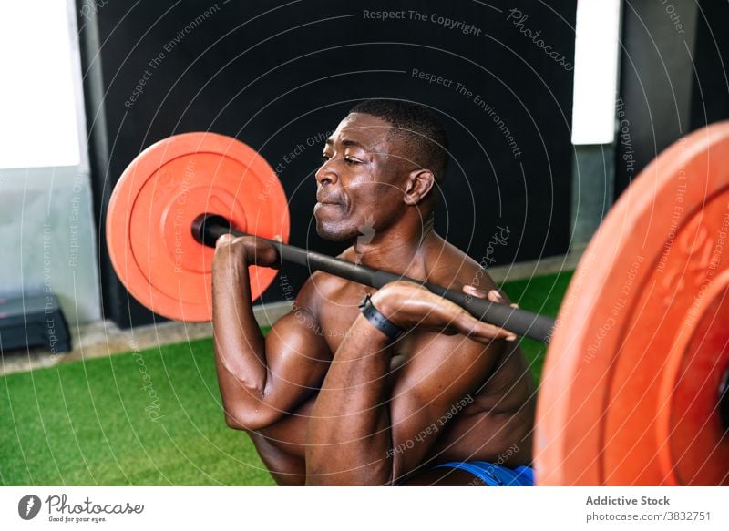 Black athletic man lifting barbell in gym weightlifting heavy sportsman muscular torso bodybuilder strong male ethnic black african american modern center