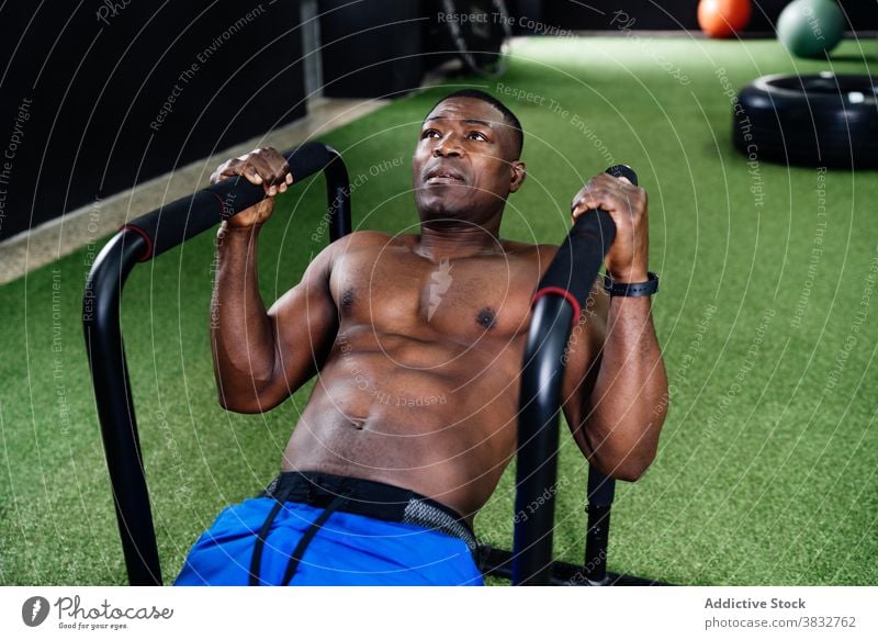 Black man doing exercises on parallel bars training bicep pump naked torso shape gym male ethnic black african american fit functional intense shirtless sport