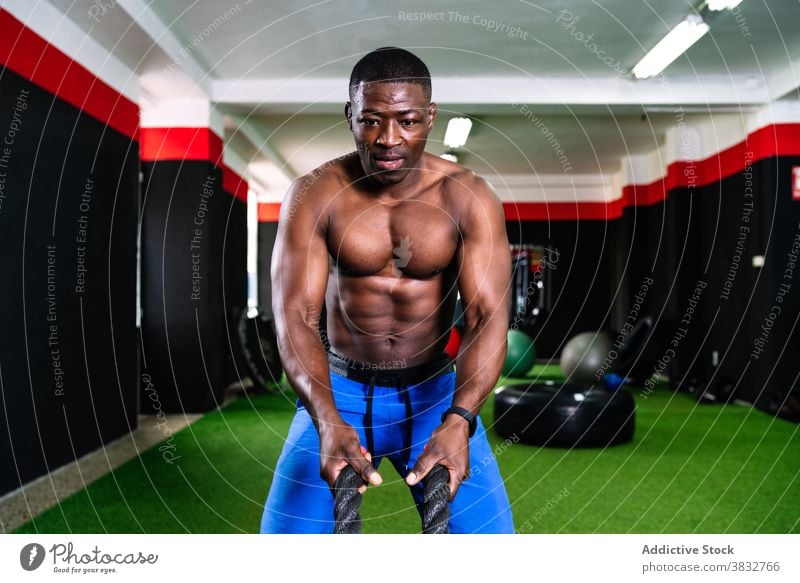Athlete doing exercises with battle ropes functional training man gym cardio effort strong sportsman male ethnic black african american strength muscular