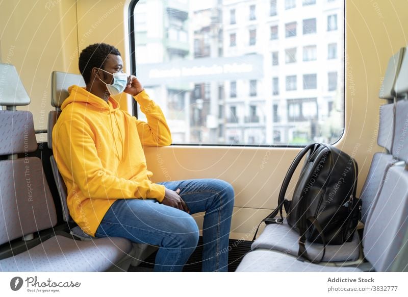 Ethnic man in medical mask sitting in modern train passenger traveler window tourist smile new normal coronavirus male ethnic black african american seat trip