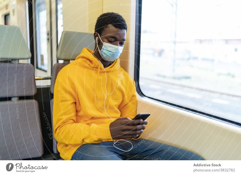 Traveling black man using cellphone in train passenger smartphone new normal travel mask coronavirus railroad railway ethnic african american tourist seat