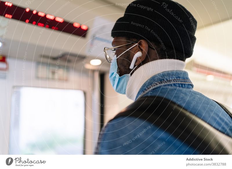 Black man in mask riding in modern train passenger door button traveler coronavirus railroad male ethnic black african american trip transport journey safety
