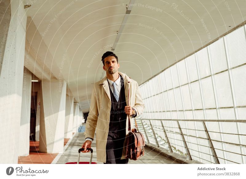 Stylish man walking along airport serious confident style suitcase pensive thoughtful corridor luggage male baggage ethnic modern departure passenger arrive