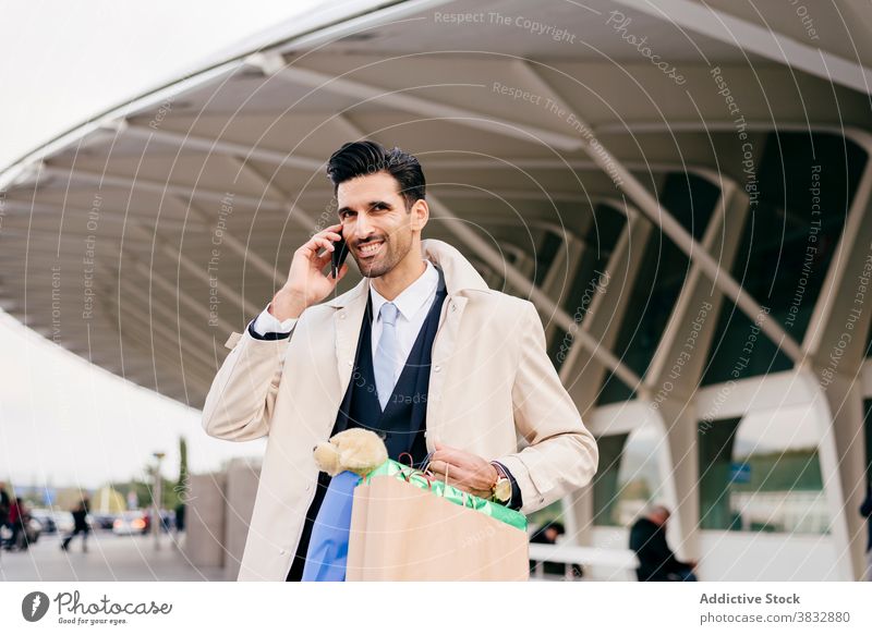 Man with shopper bags calling on phone near modern building man positive cheerful glad formal shopping bag businessman male ethnic black hair style speak