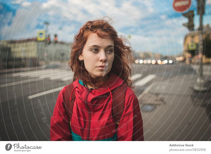 Young red haired woman standing on road in city redhead urban young wind serious millennial street curly hair long hair female saint petersburg russia travel