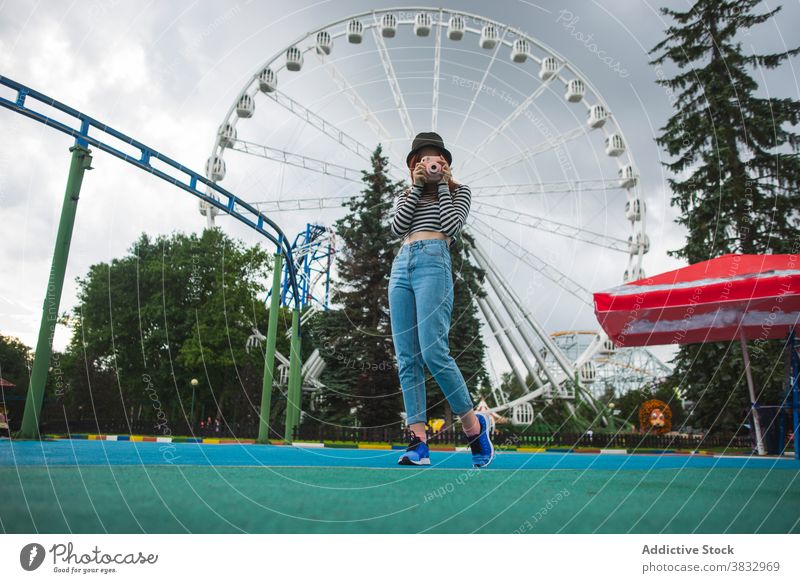 Young woman taking photos with camera in amusement park traveler take photo instant photo camera ferris wheel hipster shoot photography young tourist female