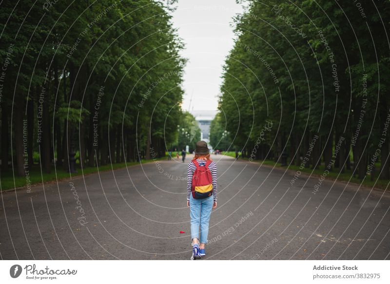 Unrecognizable young woman with backpack walking in park traveler hipster summer alley pathway journey female adventure lifestyle destination tourism road