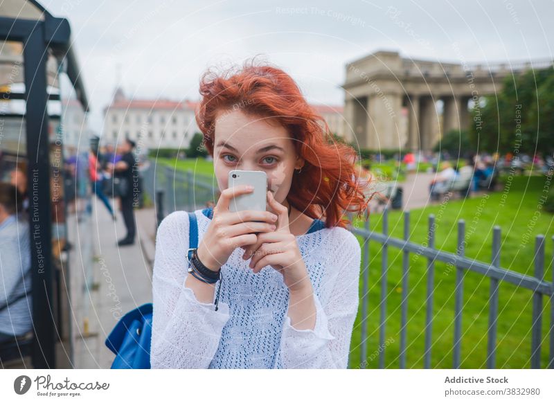 Female tourist taking photo on smartphone near old cathedral woman traveler take photo instant famous shoot photography sightseeing young redhead female