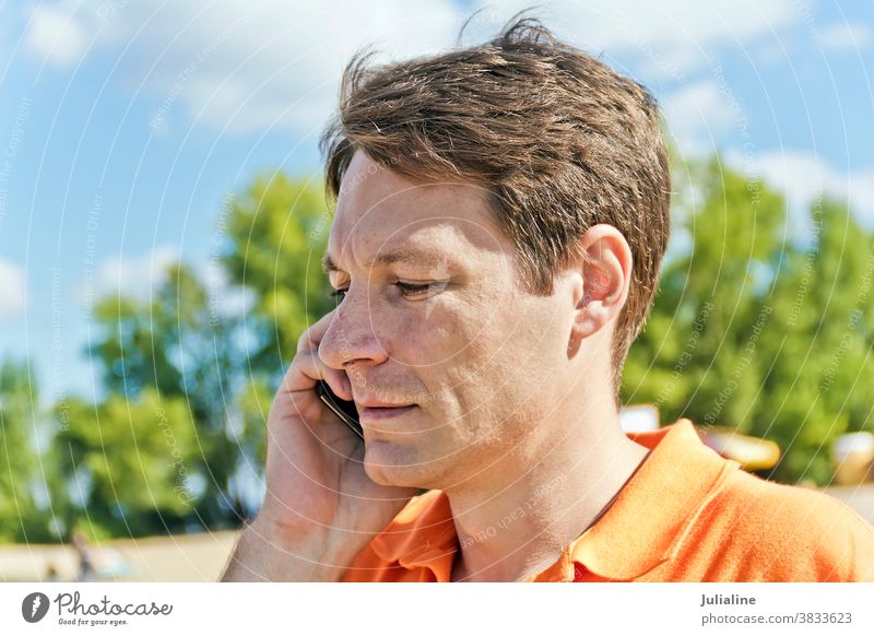 Man in orange clothes man male European Caucasian handsome talking phone mobile cellular white person brown shaten summer fall autumn outdoor casual thirty
