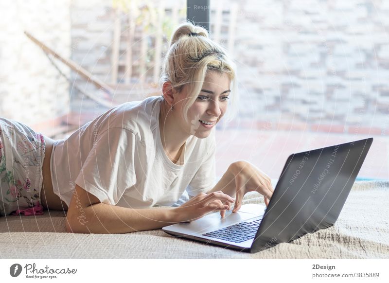 Smiling woman using a laptop while lying on her bed person teenage cyberspace happiness relaxation computer female happy home indoor pretty technology 1