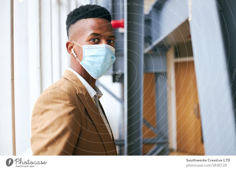 Portrait Of Young Businessman Wearing Mask Standing In Modern Office During Health Pandemic business businessman face mask face covering wearing ppe working