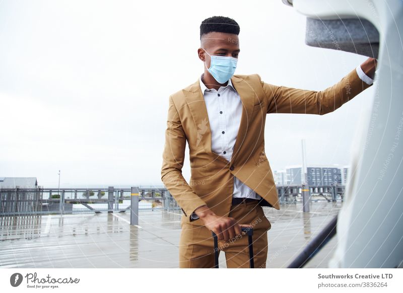 Businessman In Mask At Airport For Business Trip Taking Luggage From Car During Health Pandemic business businessman face mask face covering wearing airport