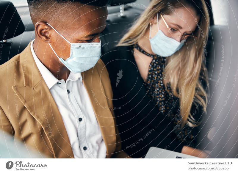 Business Couple Wearing Masks Working On Laptop In Back Of Taxi During Health Pandemic business businessman businesswoman face mask face covering wearing taxi