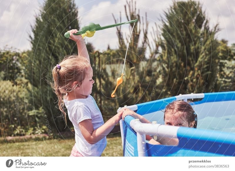 Children playing with fishing rod toy in a pool in a home garden authentic backyard childhood children family fun happiness happy joy kid laughing lifestyle