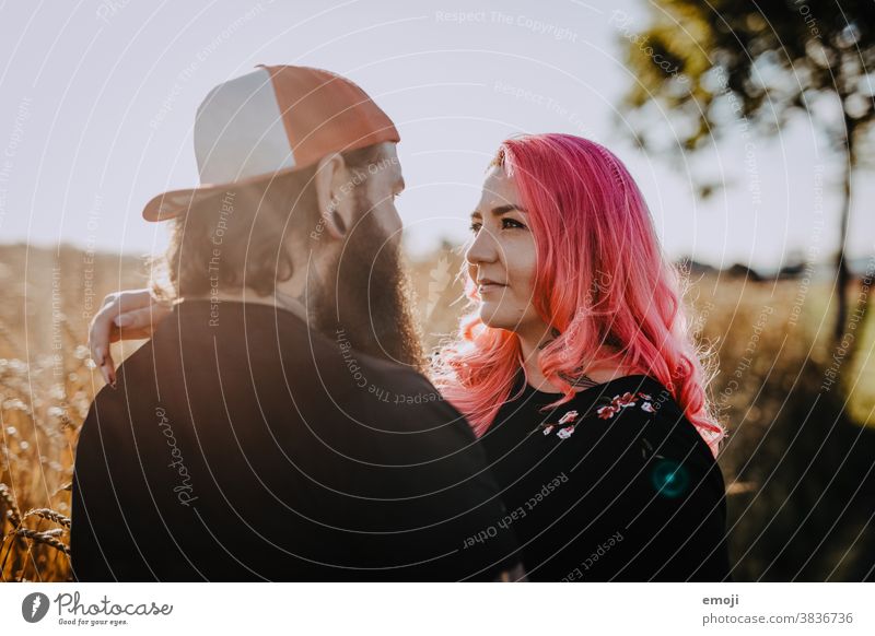 Couple with tattoos and pink hair hug and look at each other Woman Man Hipster Hip & trendy Cuddling heartfelt Tattoo Cornfield Field out Love In love Sunset