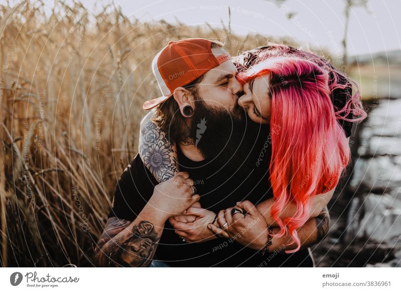 Couple with tattoos and pink hair kiss Woman Man Hipster Hip & trendy Cuddling heartfelt Tattoo Cornfield Field out Love In love hug Sunset teen proximity