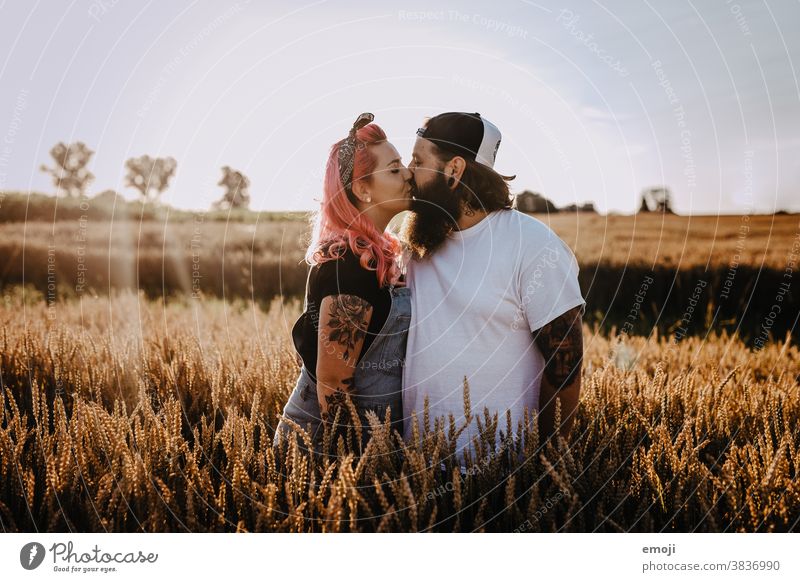 Couple with tattoos and pink hair kiss Woman Man Hipster Hip & trendy Cuddling heartfelt Tattoo Cornfield Field out Love In love Sunset teen proximity To enjoy