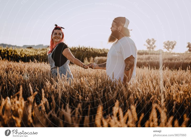young couple with tattoos and pink hair in the field at sunset teen Couple Love In love Sunset out Field Tattoo Hip & trendy Hipster Man Woman eye contact