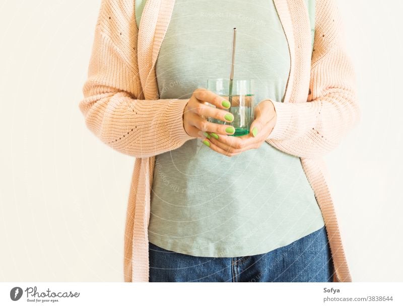 Woman holding glass of water with reusable straw zero waste woman environment eco drink plastic free stainless eco friendly pastel pink steel store sustainable