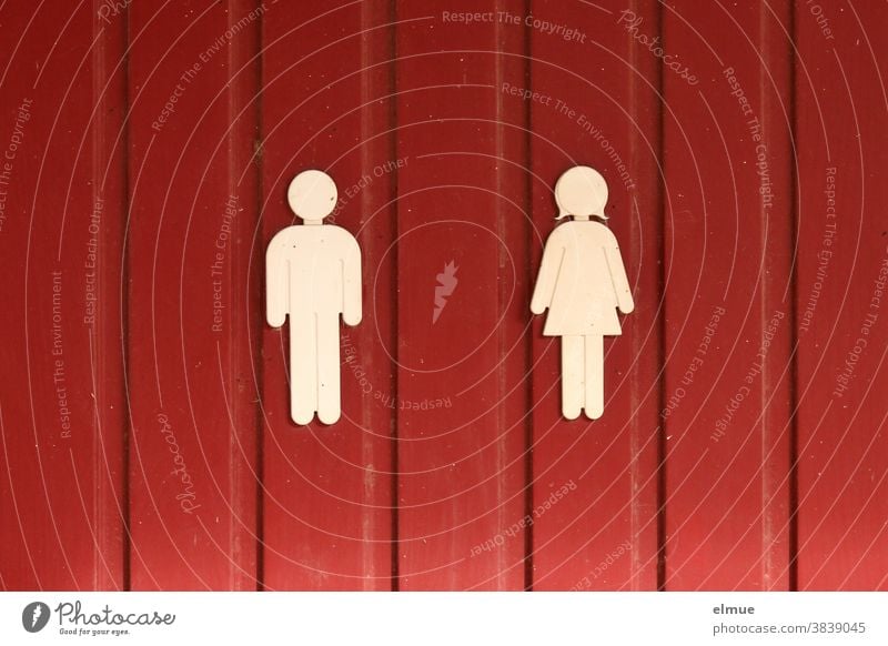 White pictograms of man and woman on a red wooden door Pictogram man and wife unisex Wooden door Abstract abstraction Allegory symbolism sign Codes