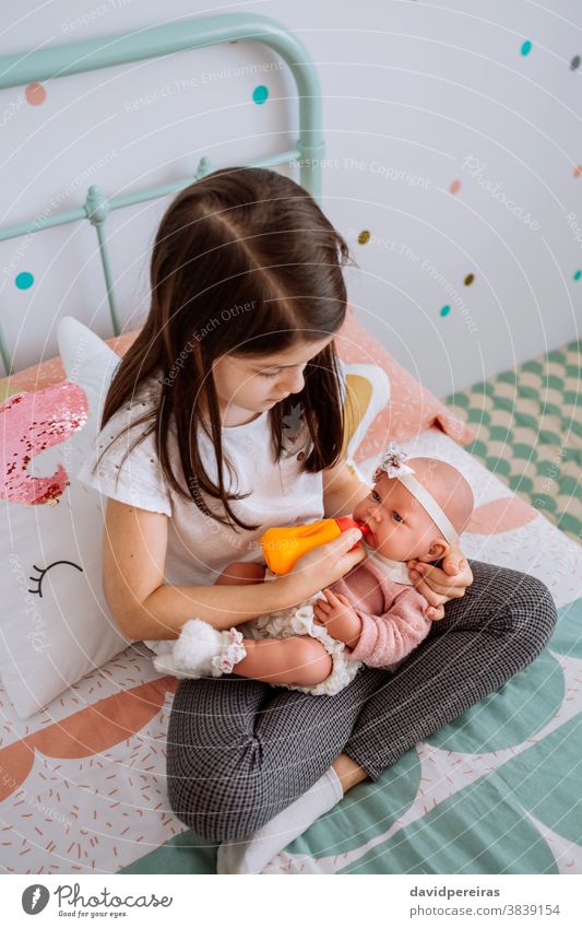 little girl playing feeding her baby doll feeding bottle imitation game traditional toys kid child cute tenderness beautiful caucasian adorable fun pretty young