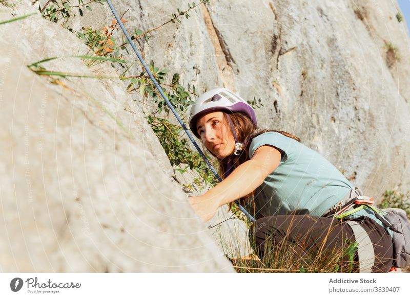 Female climber ascending on sheer cliff in summer woman alpinist mountain practice climbing active mountaineering risk travel extreme freedom adrenalin