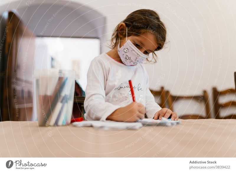 Cute girl drawing on paper at home child development kid mask quarantine coronavirus smart learn entertain table wooden concentrate focus sit creative education