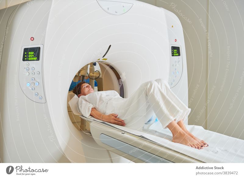 Female patient on couch of tomography equipment in clinic diagnostic professional display barefoot eyes closed woman hospital machine lying health care relax