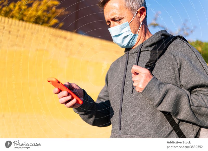 Senior retired man with face mask, sportswear and smart phone walking down the street 60 rest health care fitness training cardiac old neck rate caucasian check