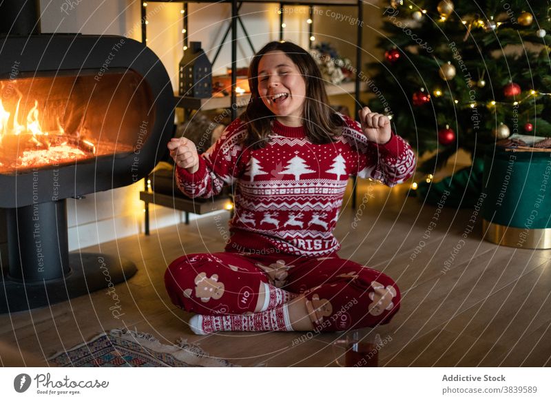 Cheerful woman in cozy Christmas sweater singing at home christmas song holiday chimney relax atmosphere merry eve female music room red smile eyes closed