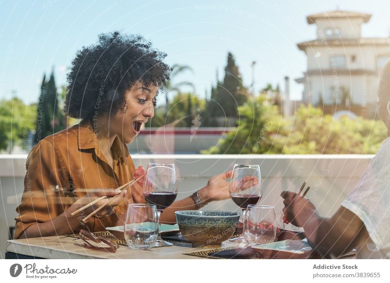 Excited black women eating sushi in restaurant asian food wonder surprise amazed wow table relax ethnic african american sit meal oriental fresh tradition