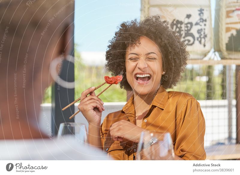 Playful ethnic women having fun while eating sushi table in restaurant chopstick laugh childish play cheerful friendship food black african american curly hair