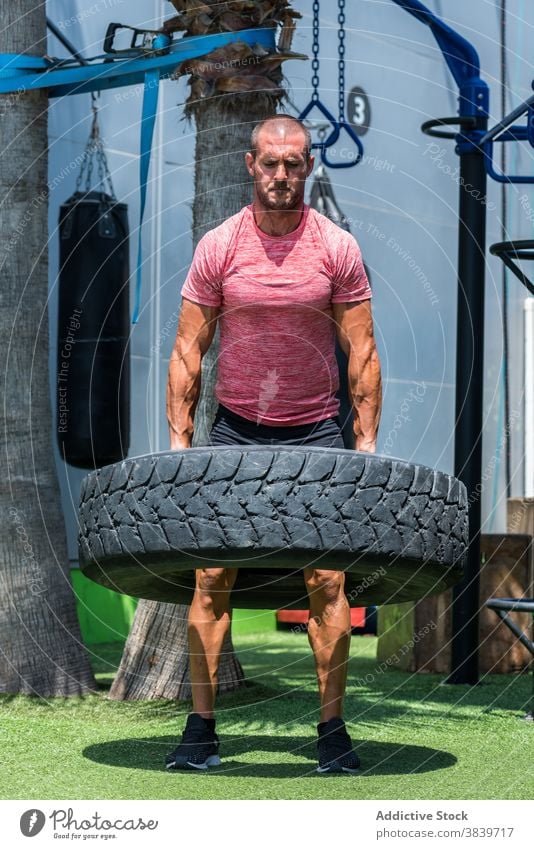 Strong sportsman doing exercises with heavy tire workout functional strong tyre lift athlete male muscular power healthy energy determine fitness active