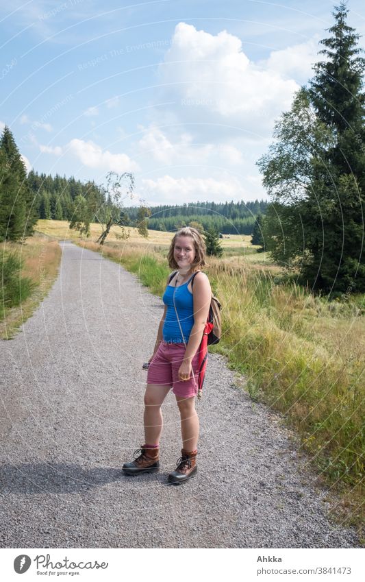 Young woman with hiking boots standing on a path in low mountain range Summer Hiking Beautiful weather Highlands Dry Green Blue Nature Trip Vacation & Travel