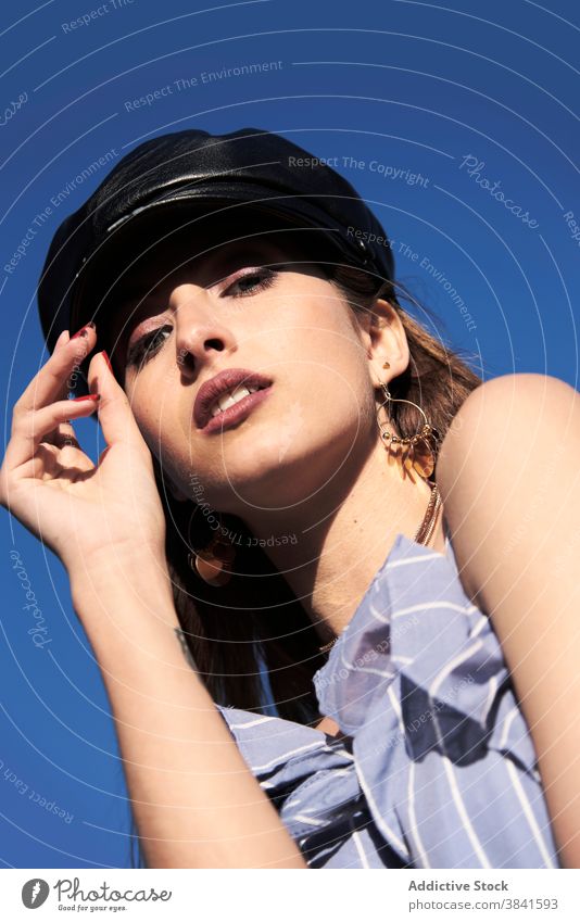 Confident woman in leather cap on sunny day headgear style material modern trendy summer model female dress outfit blue vogue sky cloth fashion blue sky