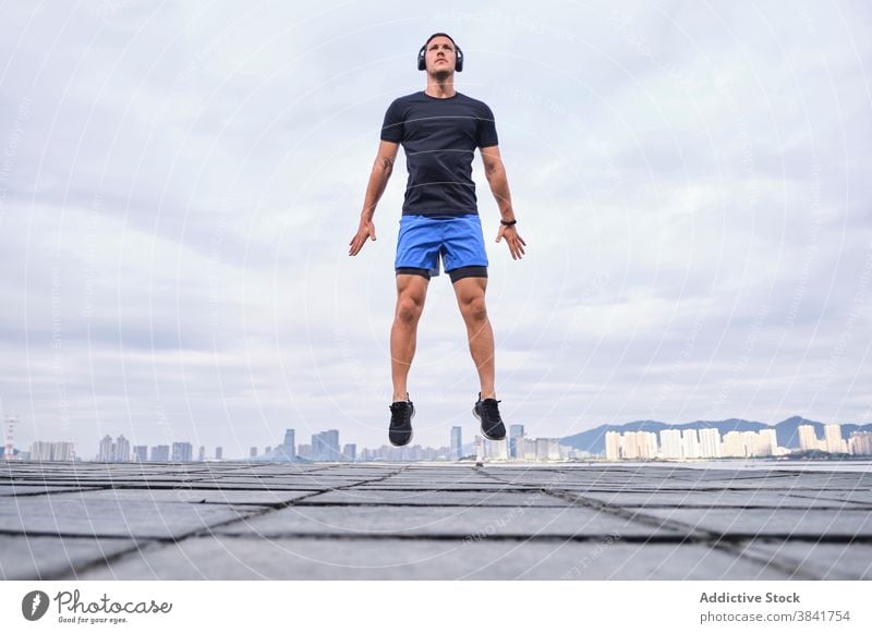 Active sportsman jumping during training in city runner warm up active cardio leap street male workout athlete fitness energy body exercise healthy urban